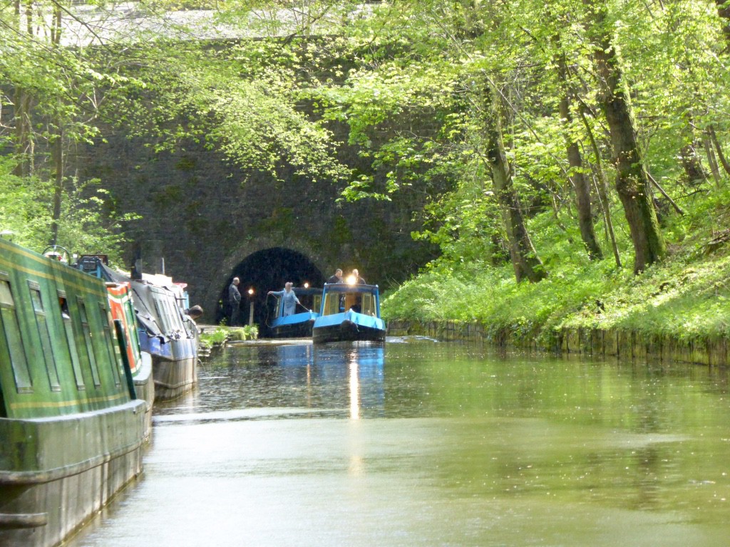 A line of boats leaving the Ellesmere tunnel.  It is so dark the only way you know who is coming is by counting the headlights