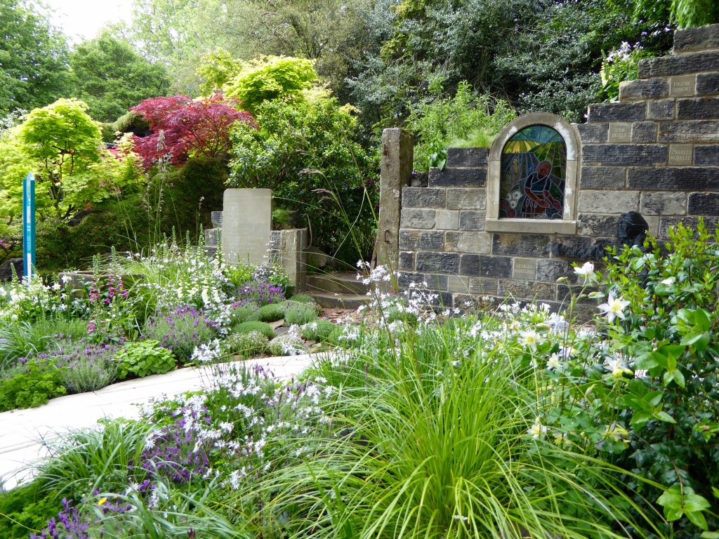 The Evaders Garden.The designer’s father was an RAF evader who was helped to freedom by ordinary French citizens after being shot down in 1943.  Inspired by these acts of selfless bravery, the garden’s design reflects the bond between helper and evader.   A sculpture of a young pilot, seconds after parachuting into France, hides in the ruins of a war-damaged church.  His eyes look up to a stained glass window where two young French people are reaching out to help him.  The wall has a code poem engraved into a tablet, along with names of Resistance fighters.   